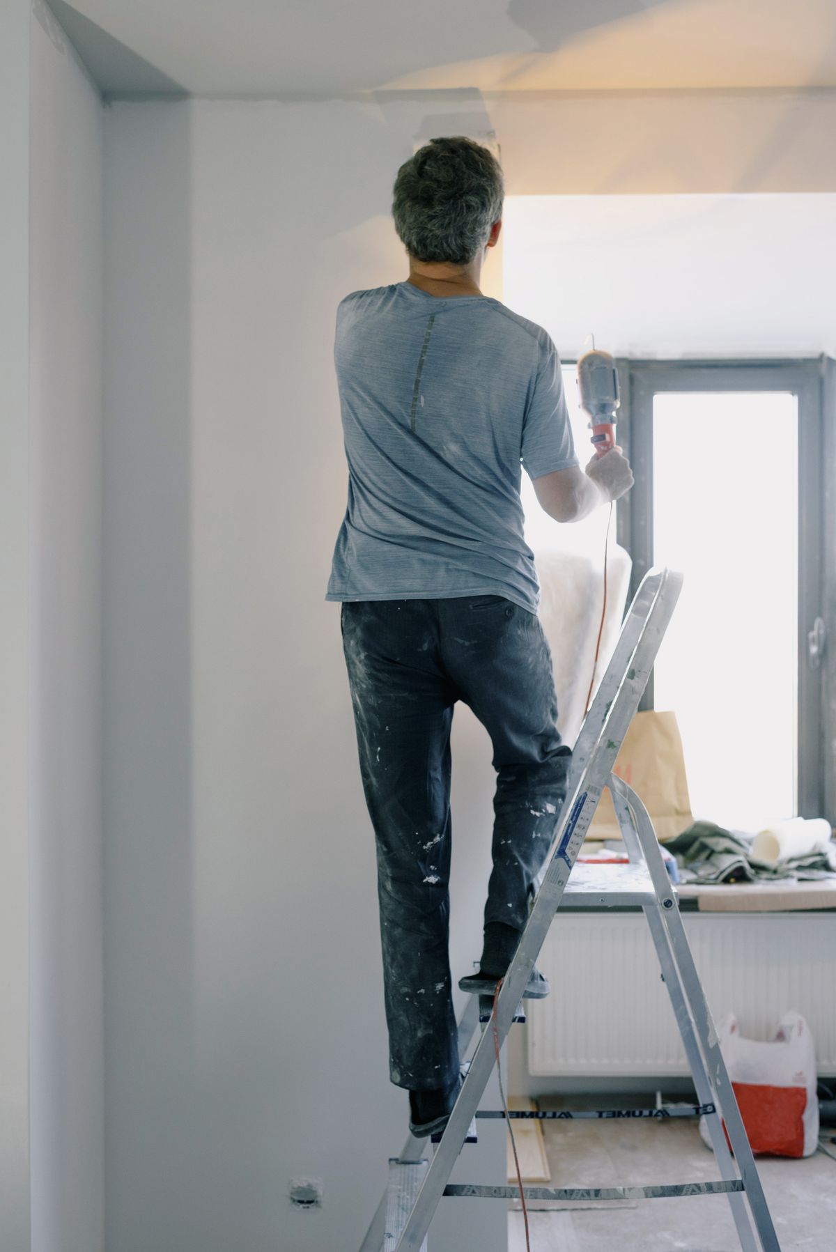 Handyman on a ladder inside an apartment during a home maintenance visit